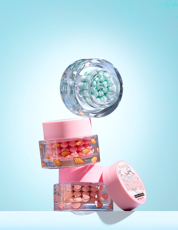 Trois petits pots avec capsule colorée de vitamine C dans un gel sur fond bleu clair
