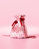 Sac à cordon rose avec nœuds rouges et motif festif avec logo « P.Louis » sur fond rose