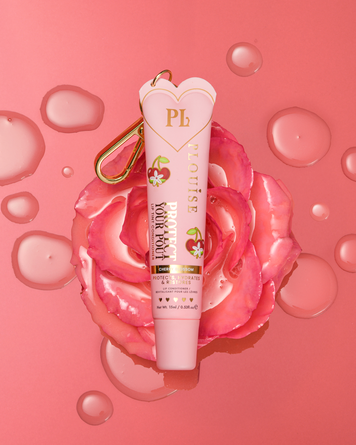 Revitalisant à lèvres teinté au parfum de fleur de cerisier rose pour protéger votre moue avec un clip doré sur une fleur rose