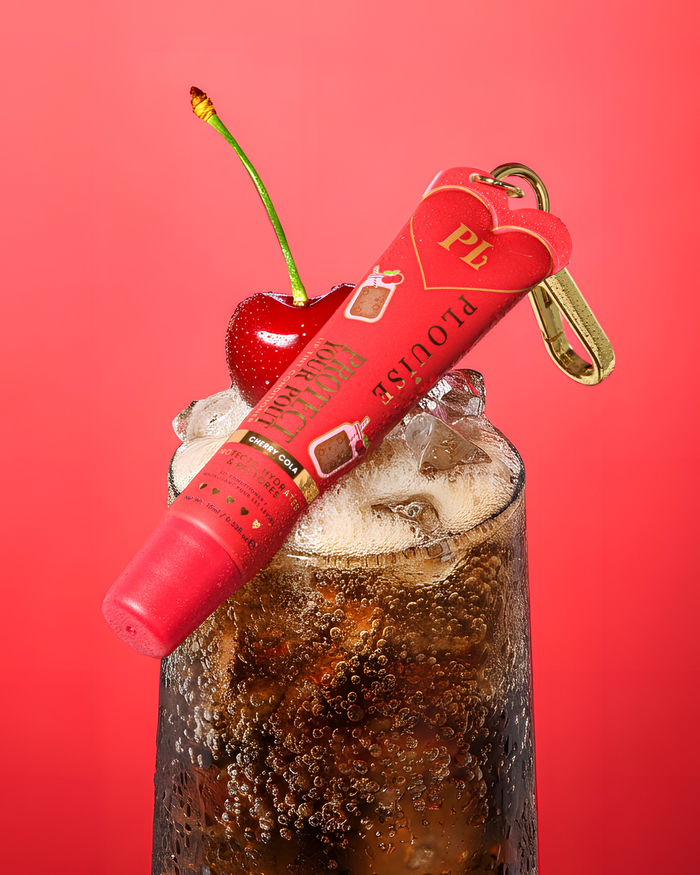 Le parfum de cerise rouge cola teinté protège votre revitalisant pour les lèvres avec un clip doré sur un verre de cola de cerise avec une cerise