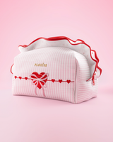 Une trousse de maquillage et de soin P.Louise à rayures roses et blanches avec des volants et un motif cœur d'amour sur fond rose