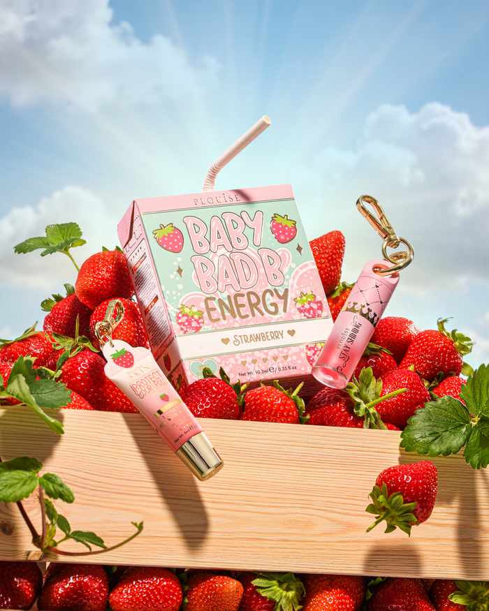 P.Louise Strawberry Baby Bad B Mini Lip Oil et Mini Lip Conditioner sur une table entourée de fraises