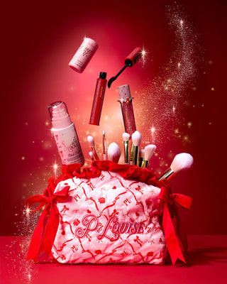 Pink Christmas P.Louise makeup bag with red festive design on it with makeup products coming out the top on a red background with gold sparkles