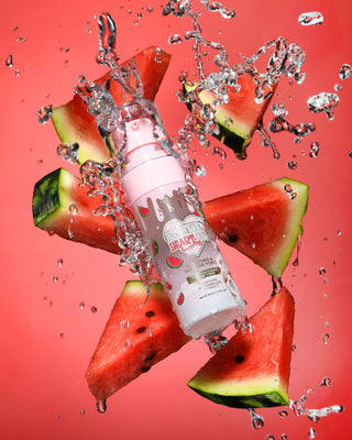 Pink bottle with watermelon design surrounded by watermelon slices and water droplets on a red background