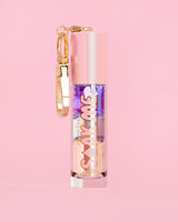P. Louise Soak Me Lip Oil avec de l'huile en couches colorées dans un tube rose avec un fermoir doré sur fond rose