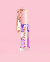 P. Louise Soak Me Lip Oil avec de l'huile en couches colorées dans un tube rose avec un fermoir doré sur fond rose