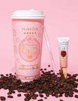 Image d'un produit représentant un crayon à sourcils à double extrémité à côté d'un tube de gel à sourcils, affiché sur une surface rose avec des grains de café éparpillés. L'arrière-plan présente une tasse à café rose avec des éléments de marque.