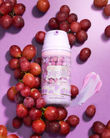 Bouteille violette de masque de récupération de raisin P. Louise Here I Glow Again entouré de raisins sur fond violet