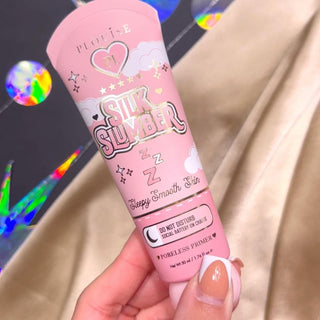 A person holding a tube of P.Louise Silk Slumber Poreless Primer with a pink background and cosmetic product details.