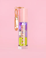 P. Louise Soak Me Lip Oil avec de l'huile en couches colorées dans un tube rose avec un fermoir doré sur fond rose