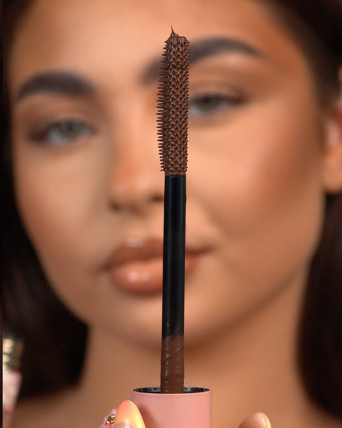 Gros plan d'une baguette de mascara imperméable P.Louise Tearproof tenue devant un visage flou